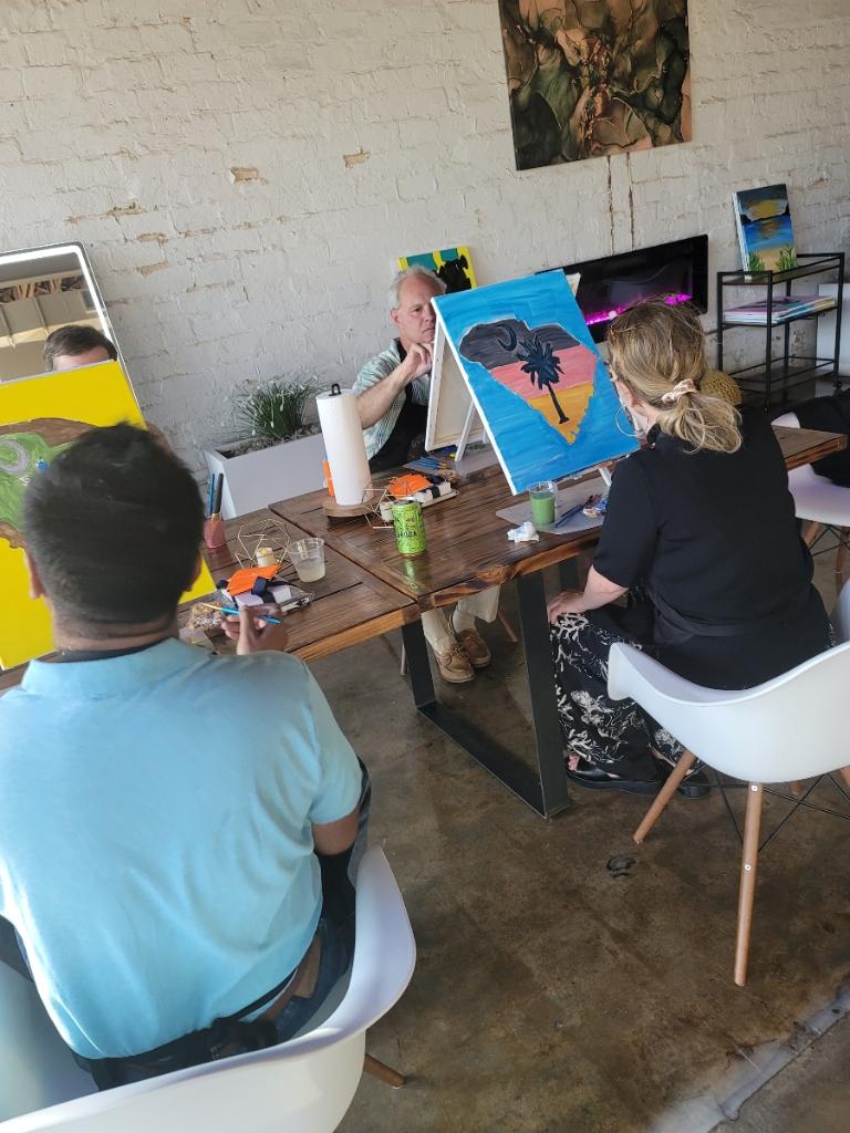 A group of people sitting around a table with paintings.