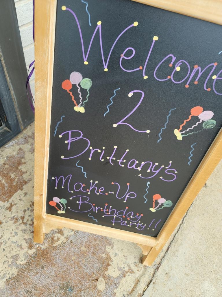 A chalkboard sign with balloons written on it.