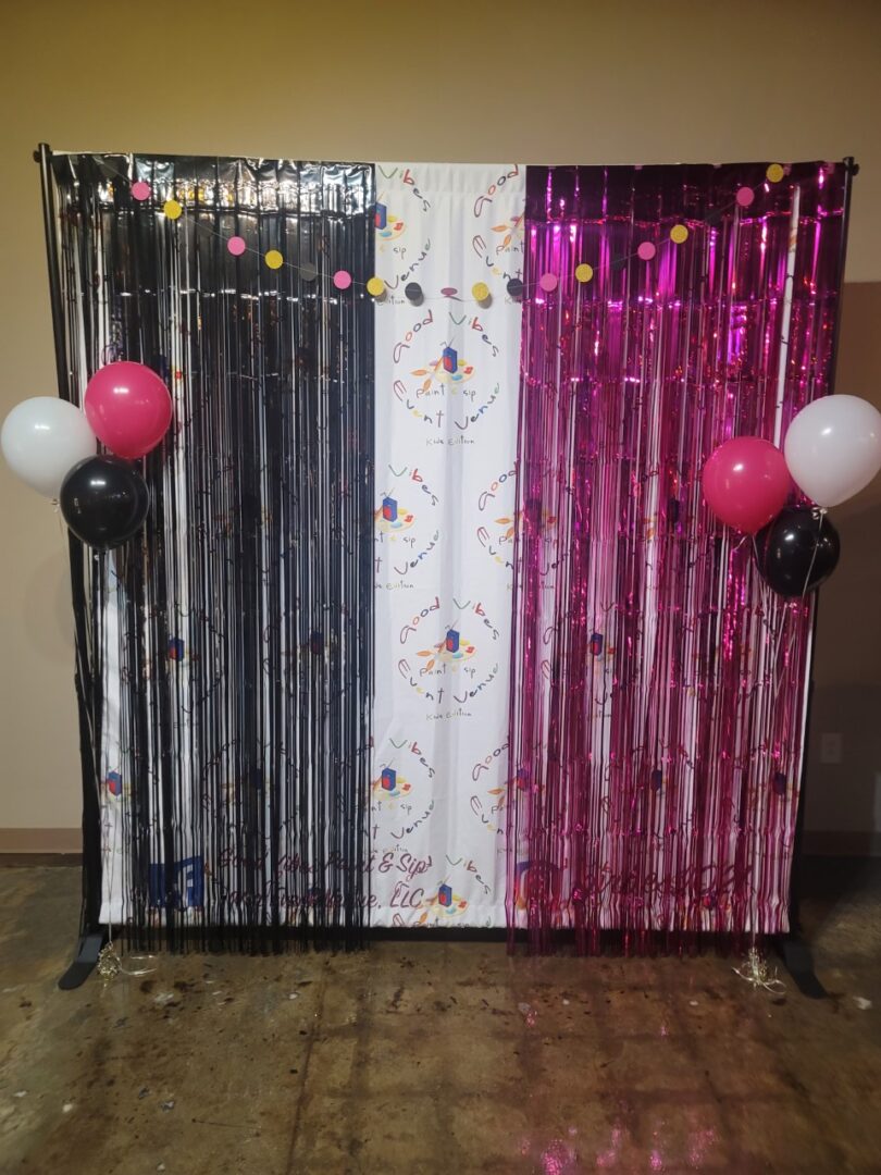A photo booth with balloons and streamers on the side.