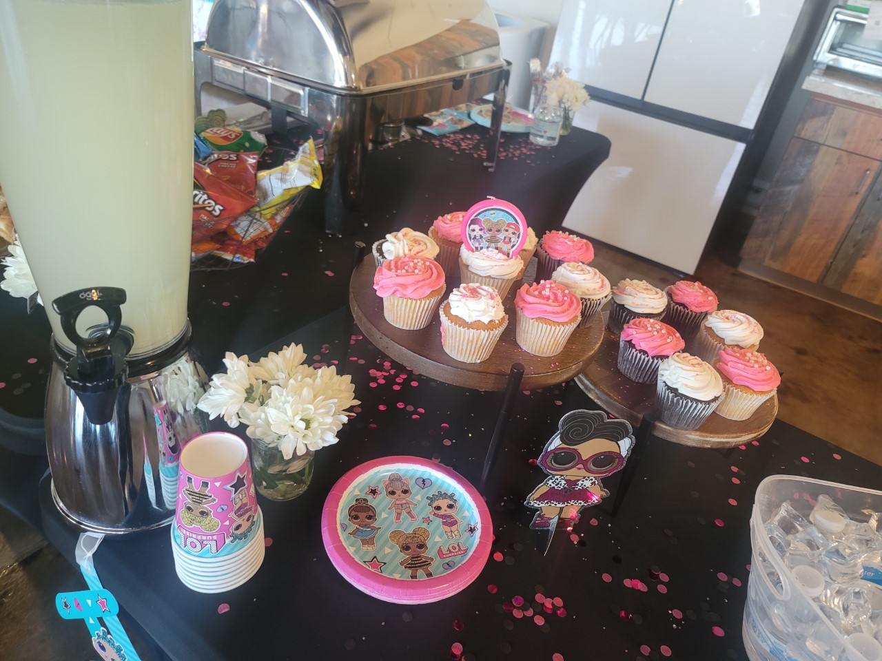 A table with several cups and cupcakes on it.