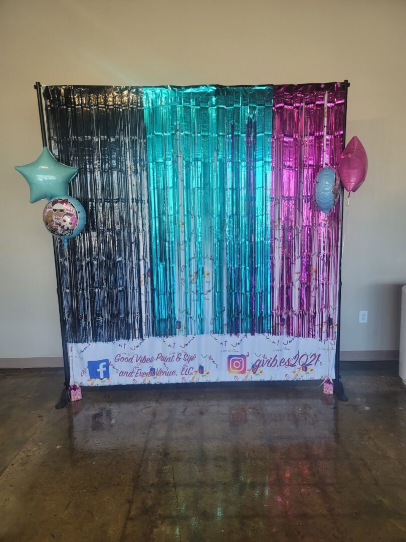 A photo booth with streamers and balloons on the floor.